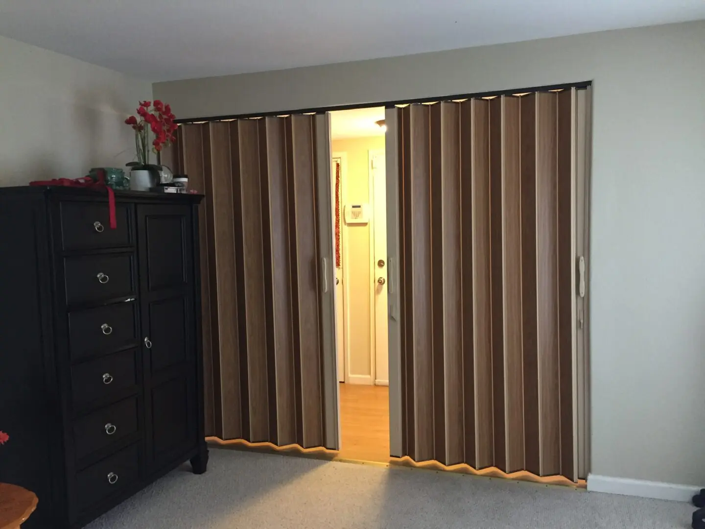 A room with two brown accordion doors and a black dresser.