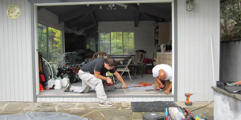 Two men working on a patio in the backyard.