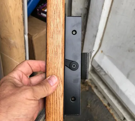 A person holding onto the door handle of their garage.