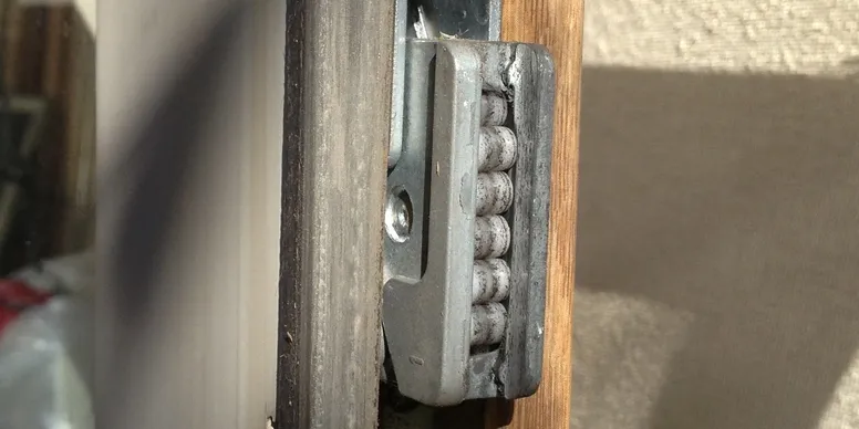A close up of the door hinge on a wooden door