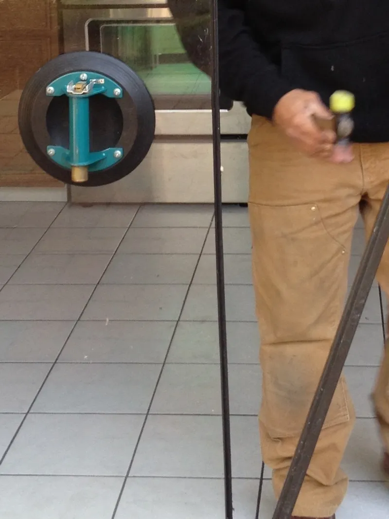 A man holding a tool standing next to a pipe.