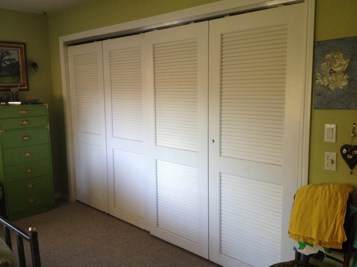 A white closet with sliding doors and a yellow towel.
